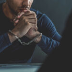 Man in handcuffs sitting at a table.