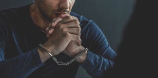 Man in handcuffs sitting at a table.