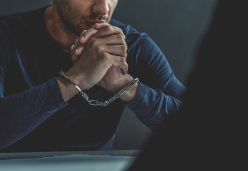 Man in handcuffs sitting at a table.