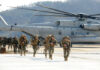 Marines walking away from helicopter on airstrip.