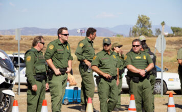 Uniformed officers standing outdoors next to traffic cones.