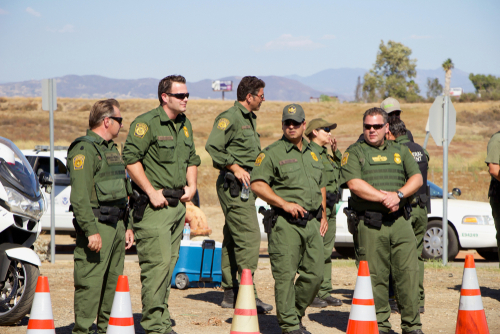 Uniformed officers standing outdoors next to traffic cones.