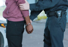 Police officer arresting a person near a vehicle.