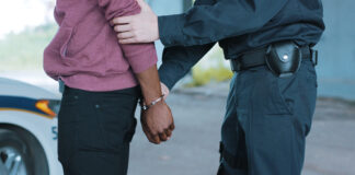 Police officer arresting a person near a vehicle.