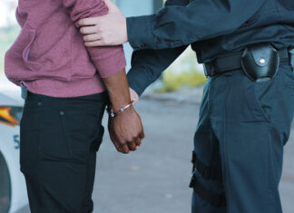 Police officer arresting a person near a vehicle.