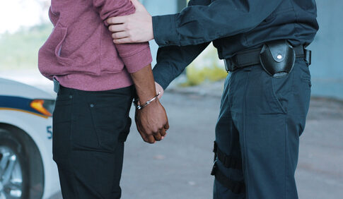 Police officer arresting a person near a vehicle.