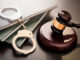 Gavel, handcuffs, and legal books on a dark surface.