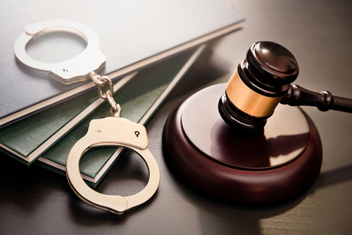 Gavel, handcuffs, and legal books on a dark surface.