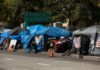 Tents and shelters line a street in a city.