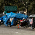 Tents and shelters line a street in a city.