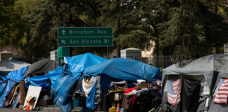 Tents and shelters line a street in a city.