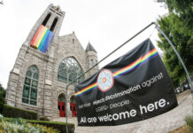 Church with rainbow flag and welcoming sign for LGBTQ+.