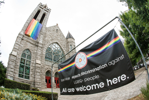 Church with rainbow flag and welcoming sign for LGBTQ+.