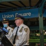 NYPD officers speak at Union Square station podium.