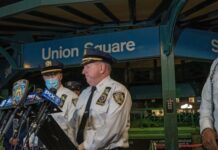 NYPD officers speak at Union Square station podium.