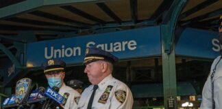 NYPD officers speak at Union Square station podium.