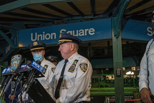 NYPD officers speak at Union Square station podium.