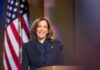 Person smiling at podium with American flag background