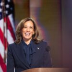 Person smiling at podium with American flag background