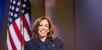 Person smiling at podium with American flag background