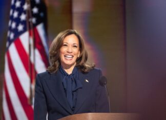 Person smiling at podium with American flag background