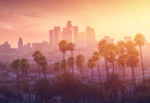 Los Angeles skyline with palm trees at sunset.