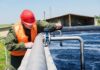 Worker inspecting water treatment plant pipes.