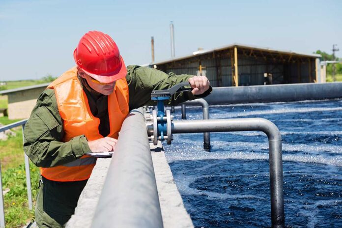 Worker inspecting water treatment plant pipes.