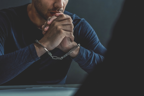 Man in handcuffs sitting at a table.