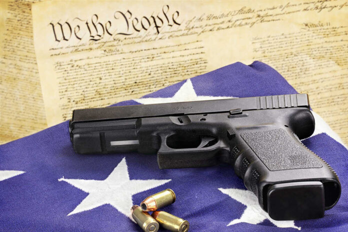 Gun and bullets on American flag with Constitution background.