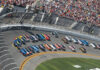 NASCAR race at Daytona Speedway with cheering spectators.