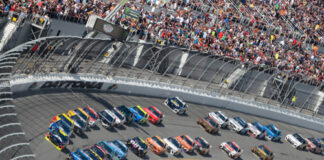 NASCAR race at Daytona Speedway with cheering spectators.