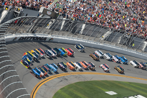 NASCAR race at Daytona Speedway with cheering spectators.