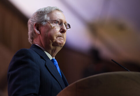 Man in glasses speaks at podium.