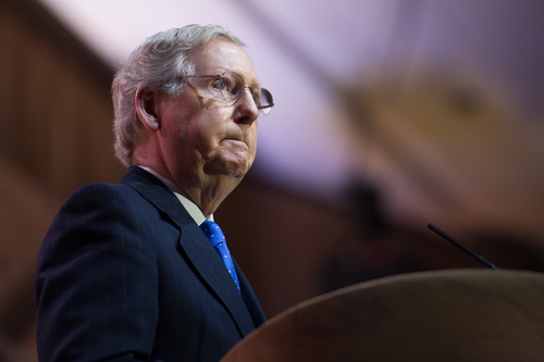 Man in glasses speaks at podium.