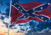 Confederate flag waving against a dramatic, cloudy sky.