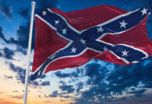 Confederate flag waving against a dramatic, cloudy sky.