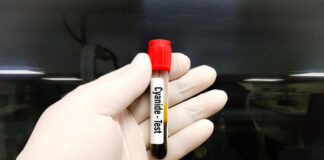 Hand holding cyanide test vial.