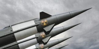 Four missiles with radiation symbols under cloudy sky.