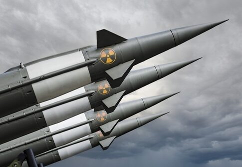 Four missiles with radiation symbols under cloudy sky.