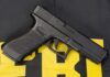 Black handgun on a yellow and black background.