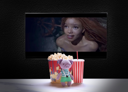 Stuffed toy with popcorn, soda, TV displaying mermaid scene.