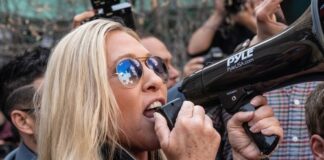 Woman shouting into megaphone while in a crowd.