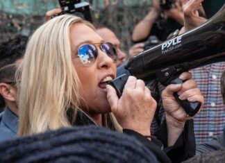 Woman shouting into megaphone while in a crowd.