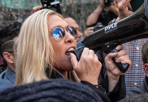 Woman shouting into megaphone while in a crowd.