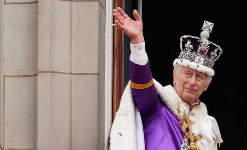 King Charles III in coronation attire waving.