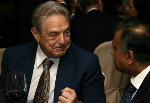 Two men in suits conversing at an event.