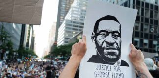 Person holding "Justice for George Floyd" sign at protest.