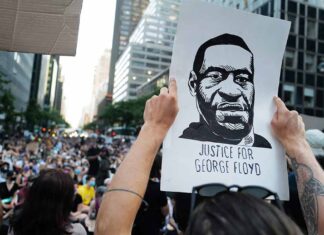 Person holding "Justice for George Floyd" sign at protest.