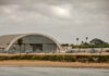 Hangar with military helicopters near a beach.